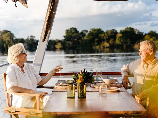 Ein älteres Paar genießt ein romantisches Essen und Getränke auf einem Boot auf dem Sambesi.