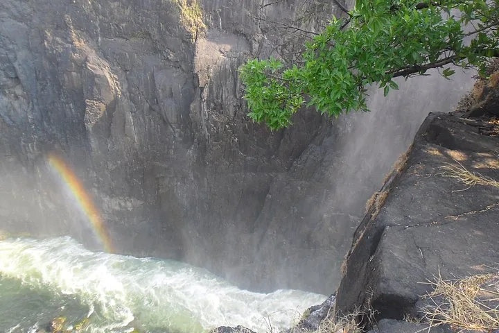 Ein Abschnitt der Victoriafälle, der mit einem Regenbogen über eine steile Felswand stürzt.