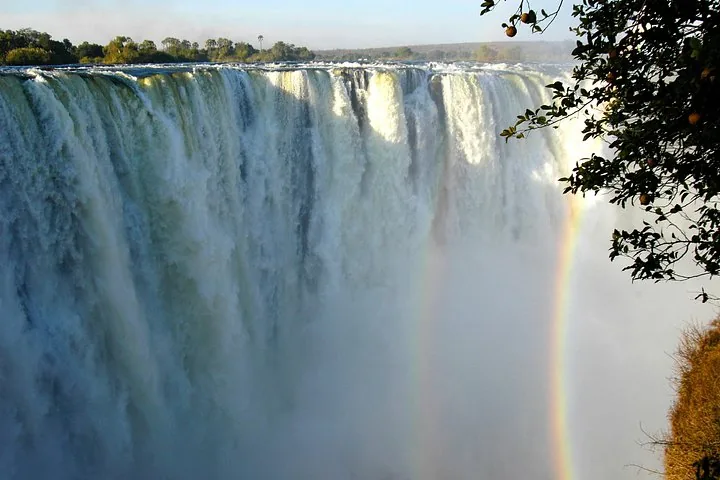 A stunning view of Victoria Falls cascading down the rocks with a beautiful rainbow.